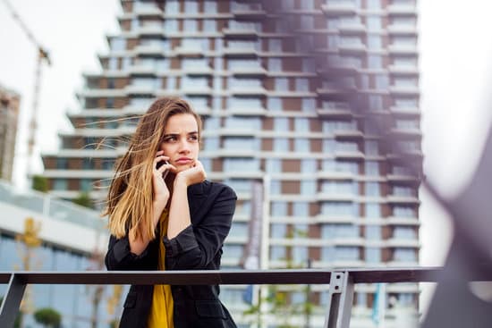 Businesswoman with a mobile phone in the street with office buil